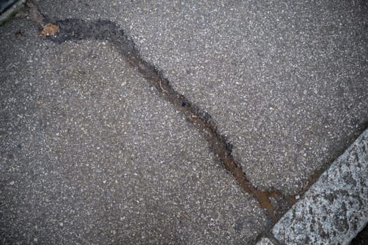 Cremona, Italy - November 27th 2024 Close-up of a damaged asphalt road with a long crack, highlighting the need for road maintenance in cremona, italy