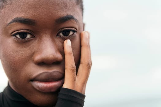 close up portrait of an african american young woman with short hair touching face in daylight, concept of beauty, copyspace for text