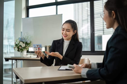 A businessman in a modern office setting signs a contract for purchasing a house, symbolizing real estate transactions and professional business dealings.