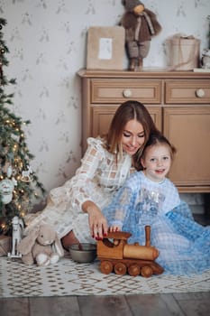 Smiling girl with mom near christmas tree at home.