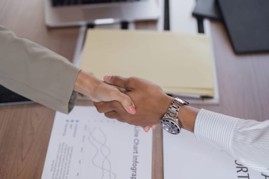 Two businessmen shake hands in a modern office, symbolizing successful collaboration and partnership.