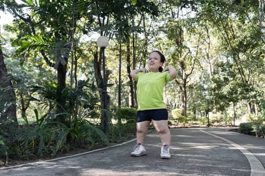 A person with a small body energetically stretches muscles while exercising in a tranquil park environment.