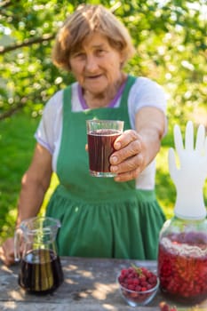 Grandma makes wine from raspberries in the garden. Selective focus. drink.