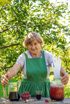 Grandma makes wine from raspberries in the garden. Selective focus. drink.