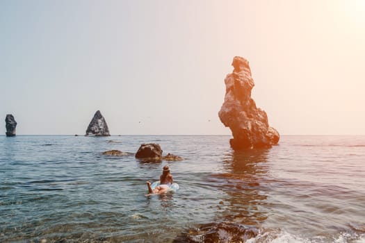 Woman summer sea. Happy woman swimming with inflatable donut on the beach in summer sunny day, surrounded by volcanic mountains. Summer vacation concept