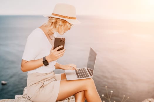 Digital nomad, Business woman working on laptop by the sea. Pretty lady typing on computer by the sea at sunset, makes a business transaction online from a distance. Freelance remote work on vacation