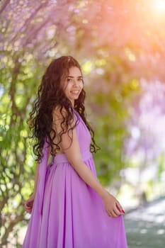 Woman wisteria lilac dress. Thoughtful happy mature woman in purple dress surrounded by chinese wisteria.