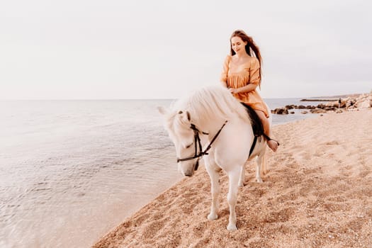 A woman in a dress stands next to a white horse on a beach, with the blue sky and sea in the background