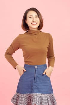 Attractive young Asian woman smiling isolated over pink background.