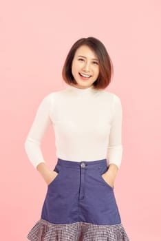 portrait of smiling Asian woman standing isolated on pink background.