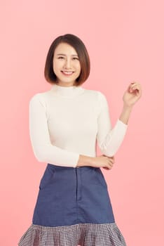 Cheerful young beautiful Asian woman showing her hand while standing over pink background.