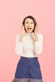 Portrait of an excited asian businesswoman looking at camera isolated over pink background