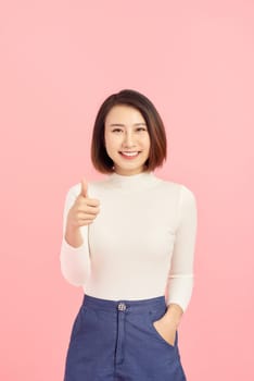 Young Asian woman show thumbs up on pink background