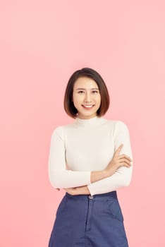 Young Asian woman wearing  sweater standing over isolated pink background happy face smiling with crossed arms looking at the camera. Positive person.