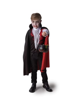 Boy in Halloween vampire makeup costume holding cauldron with sweets isolated on white background