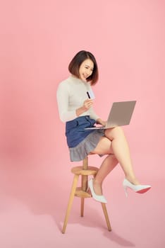 Beautiful woman holding credit card to payment online by her laptop.