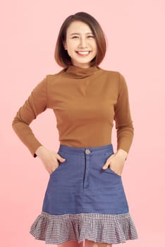 Cheerful young Asian businesswoman standing isolated on pink background.