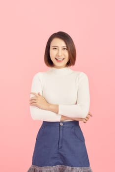 Smiling of Asian woman crossing her arms and standing isolated on pink background.