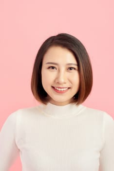 Portrait of young confident Asian woman on pink background.