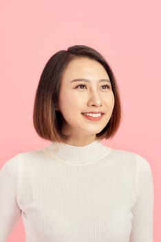 Portrait of young confident Asian woman on pink background.