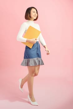 Full-length portrait of businesswoman with folder, isolated on pink. Concept of leadership and success