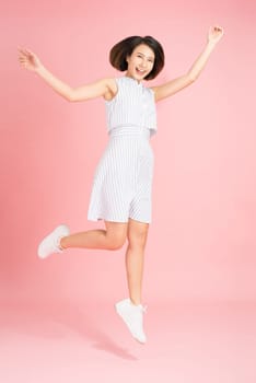 Freedom in moving. Surprised, pretty, happy young woman jumping and gesturing against pink studio background