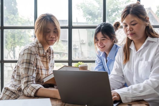 Asian College groups of students using laptop, tablet, studying together with notebooks documents paper for report near windows in classroom. Happy young study for school assignment