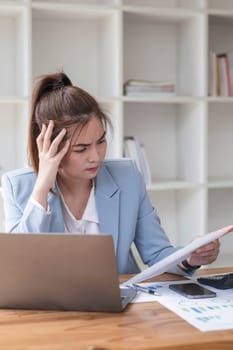 Confused Asian woman thinking hard about how to solve problems online looking at laptop screen. Serious Asian businesswoman worried focused on solving difficult computer at office.
