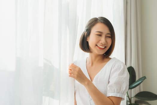 Beautiful woman in white silk robe standing near window