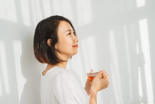 Happy woman thinking and looking at side beside a window at home