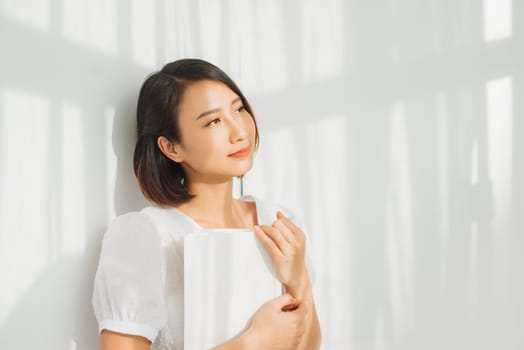 Young woman reading a book while relaxing at home with sunlight.