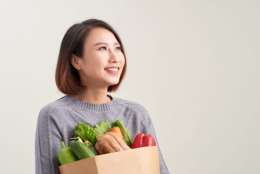 Cheerful woman holding a shopping bag full of groceries