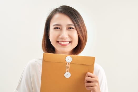 A woman is holding and giving a big brown envelope with blank space on it