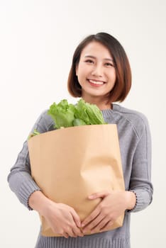 Cheerful woman holding a shopping bag full of groceries