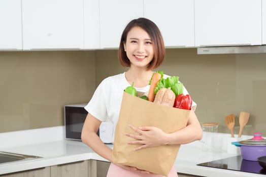 Happy Young Asian Woman with vegetables in shopping bag. Diet concept. 