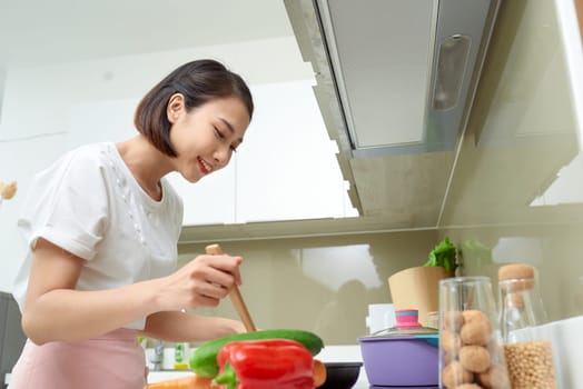 Cooking woman in kitchen with wooden spoon