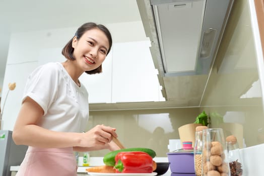 Happy Asian woman cooking in the kitchen.