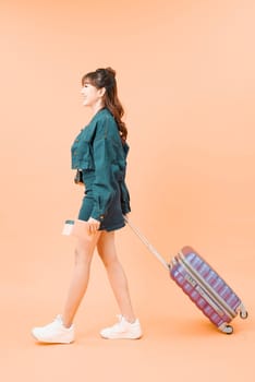 smiling young woman with airplane ticket and bag