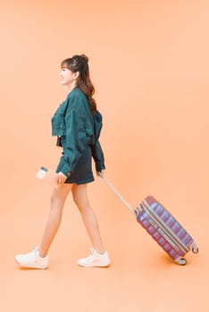 Girl with a suitcase going traveling on color background