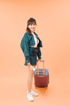 Girl with a suitcase going traveling on color background
