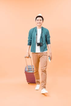 Full body portrait of travel man with bag pulling suitcase
