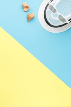 Beach hat with sunglasses and seashells on bicolor isolated background. Top view. Summer vacation concept. Flat lay.