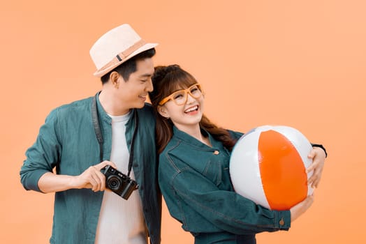 Lovely Asian couple in summer casual clothes and beach accessories studio shot isolated on yellow background