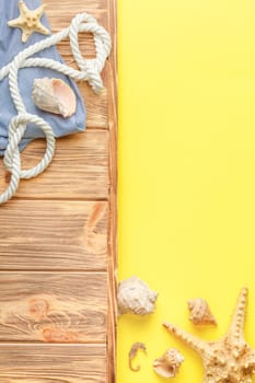 Nautical rope and striped tunic on wooden background with yellow copy space. Flat lay. Summer vacation concept. Starfish and seahorse. Top view.