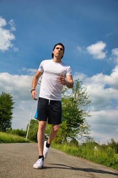 A man running down a road in the countryside in a sunny summer day