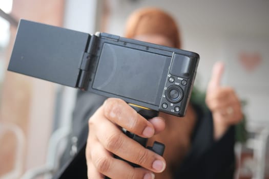 An individual proudly demonstrating a camera and giving a friendly thumbs up gesture