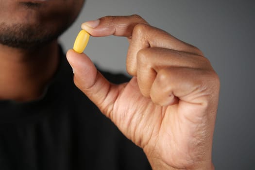 A person holds a yellow capsule, emphasizing the importance of health and wellness