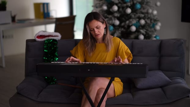 A young woman joyfully enjoys playing a colorful keyboard in a modern, festive holidaythemed living room setting