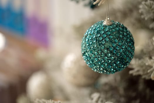 A stunning turquoise ornament, adorned with shimmering and sparkling gems, beautifully hangs on a festive tree
