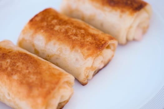 Golden fried rolls with savory fillings, elegantly presented on a white plate for a perfect dining experience